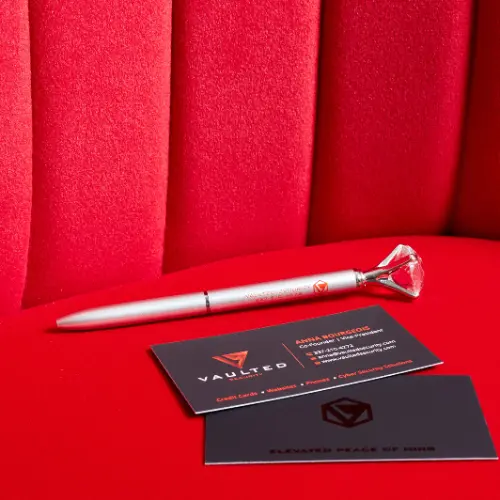 A pen that says Vaulted Security with a crystal at the end and black business cards with the Vaulted Security logo and Anna's contact info.